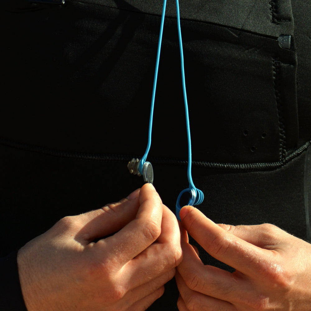 Hands connecting a blue earplug leash to earplugs in close-up.